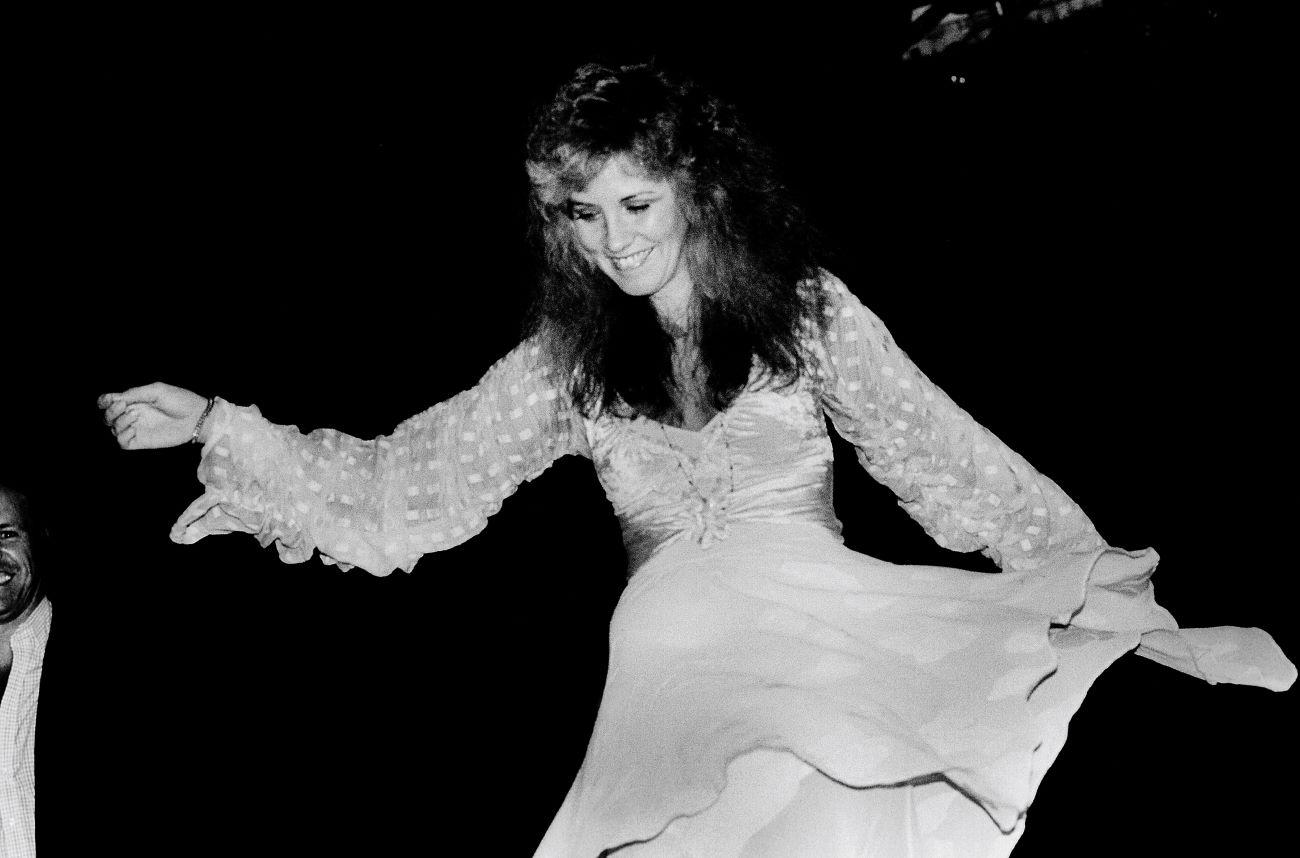 A black and white photo of Fleetwood Mac artist Stevie Nicks wearing a long sleeve dress.