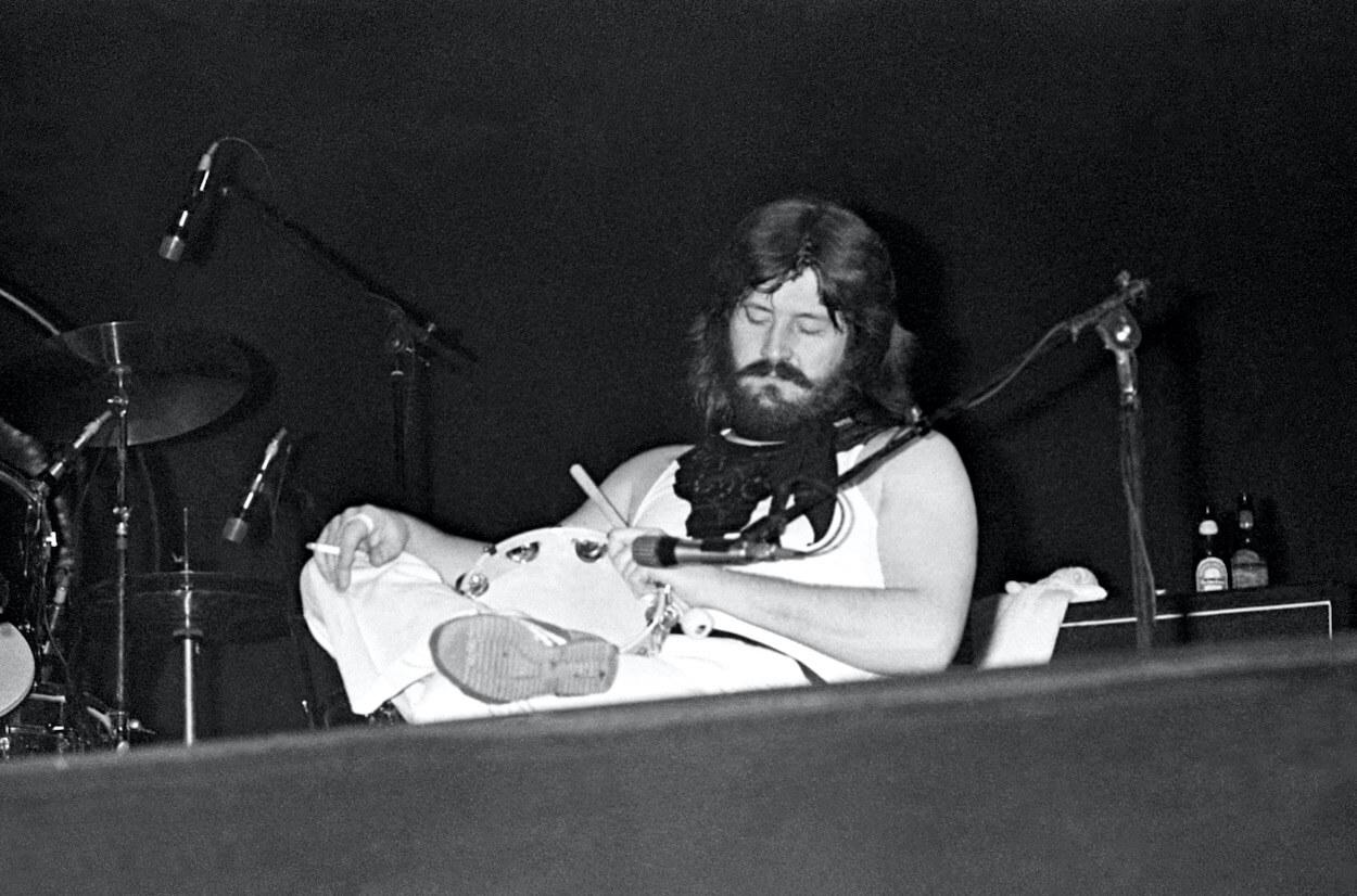 Led Zeppelin drummer John Bonham holding a cigarette and tambourine as he pretends to sleep during a 1975 concert.